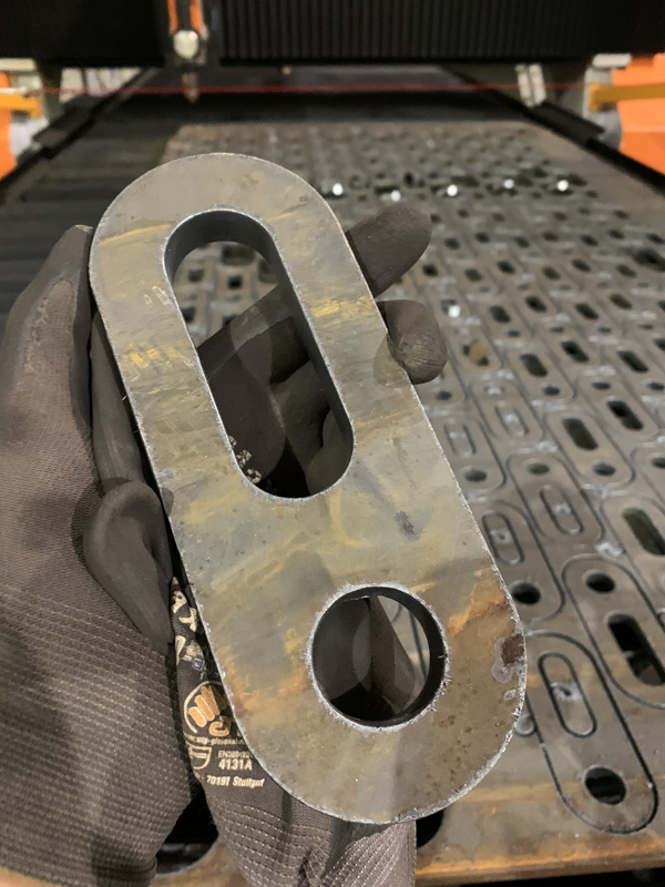 Close up image of a plate with a hole and slotted hole detailing percise cutting
